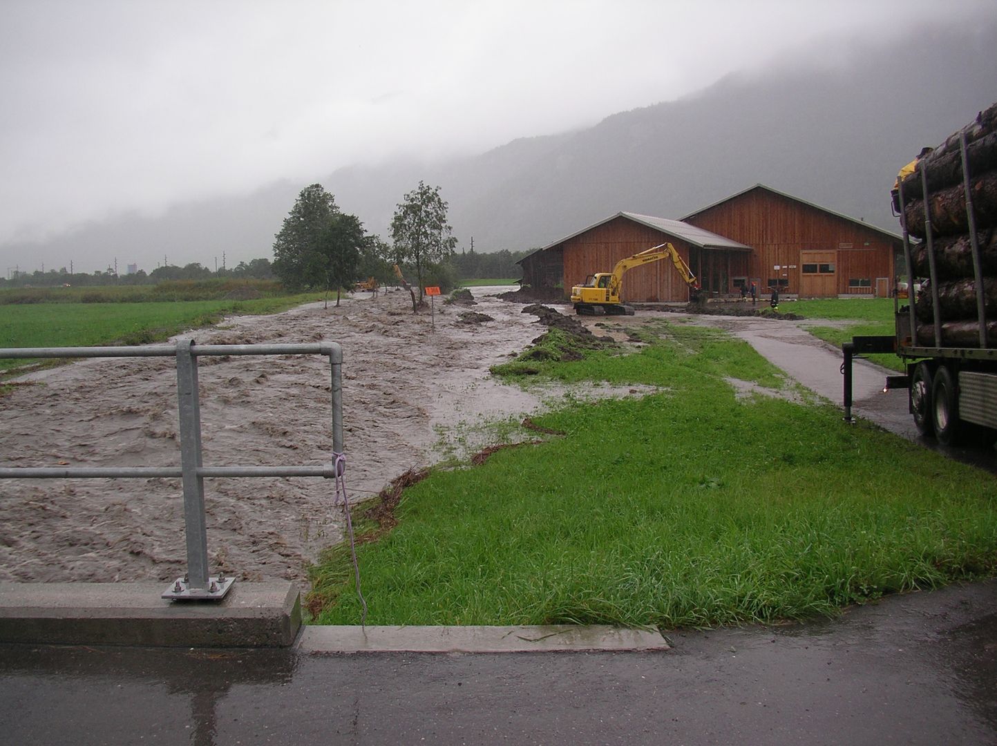 Blick von einer Brücke auf Hochwasser im Rychenbach vor der Revitalisierung. Das Wasser fliesst auf die Wiesen.